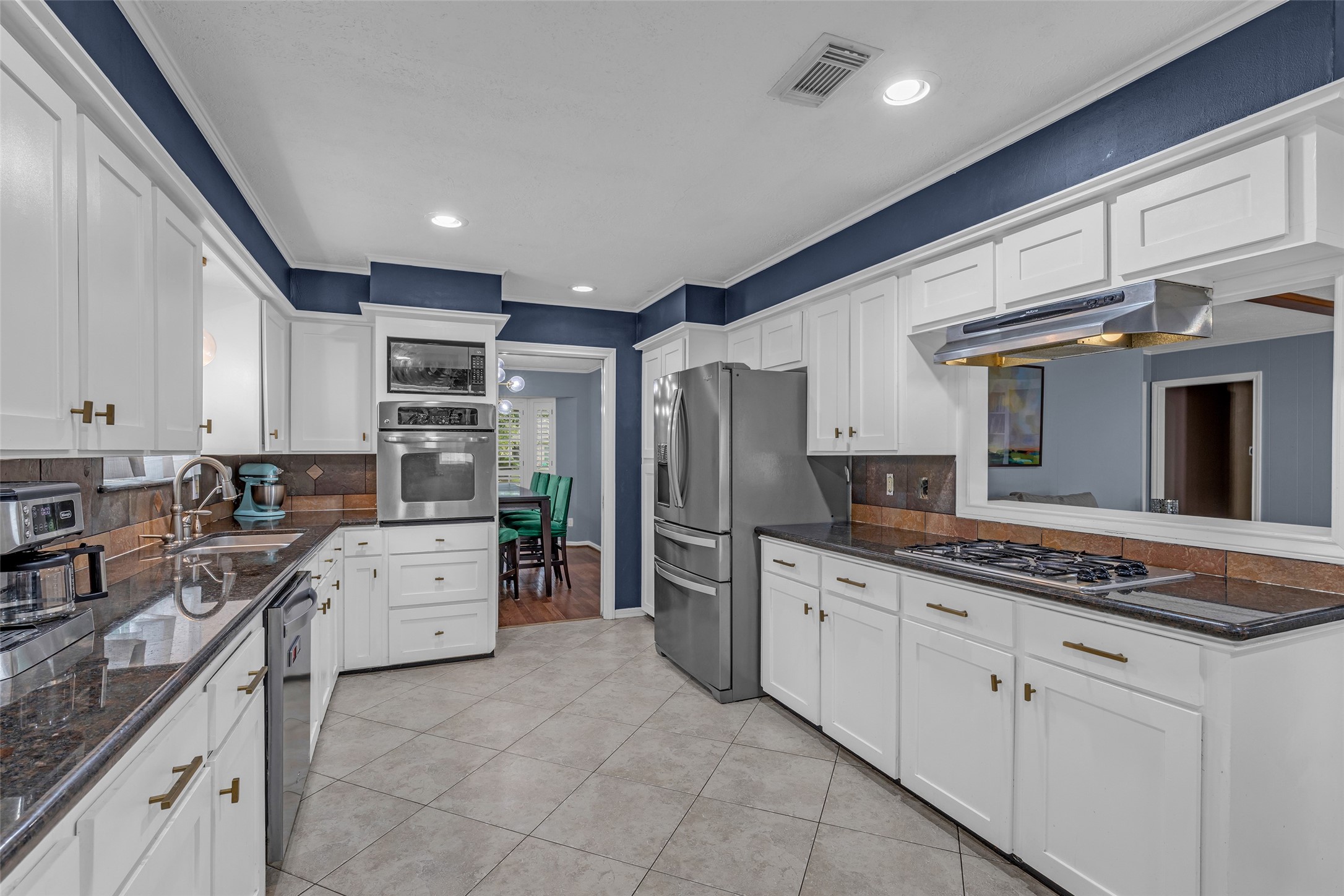 947 Thornton Road Houston, TX 77018 - Photo 6 of 34 Spacious kitchen with sleek stainless steel appliances, ample white cabinetry, and elegant dark countertops, offering a perfect blend of style and functionality.