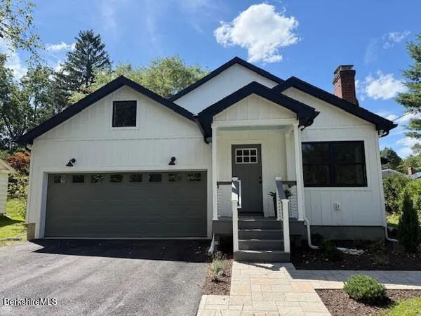 a view of a white house with a big yard and large trees with wooden fence