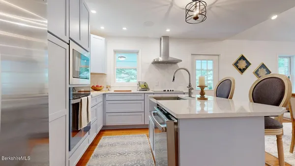 a kitchen with kitchen island granite countertop a sink stainless steel appliances and cabinets