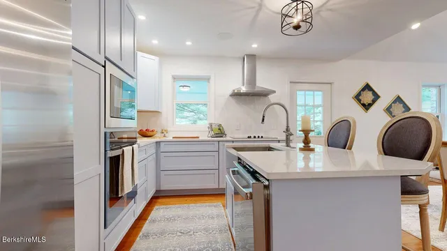 a kitchen with kitchen island granite countertop a sink stainless steel appliances and cabinets