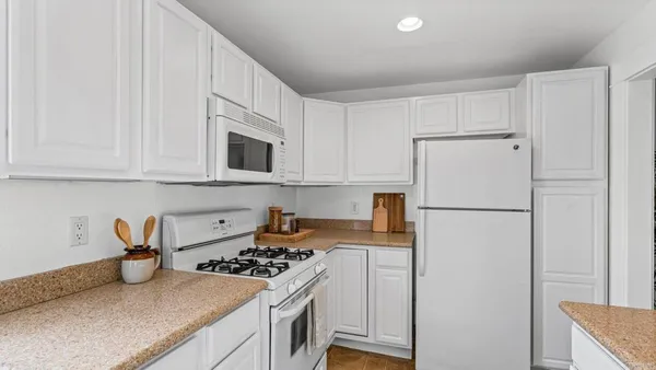 a kitchen with stainless steel appliances granite countertop a refrigerator stove a sink and white cabinets