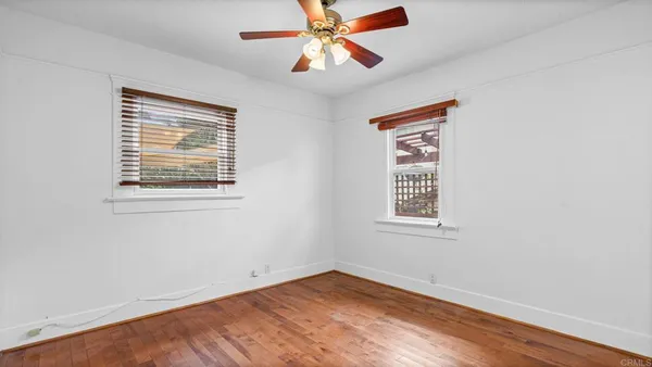 a view of an empty room with window and wooden floor