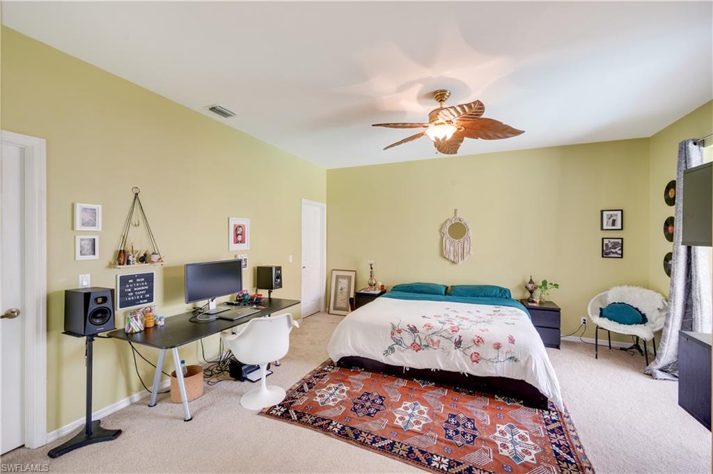 5738 Lago Villaggio Way Naples, FL 34104 - Photo 6 of 28 a bedroom that has a bed and a chandelier