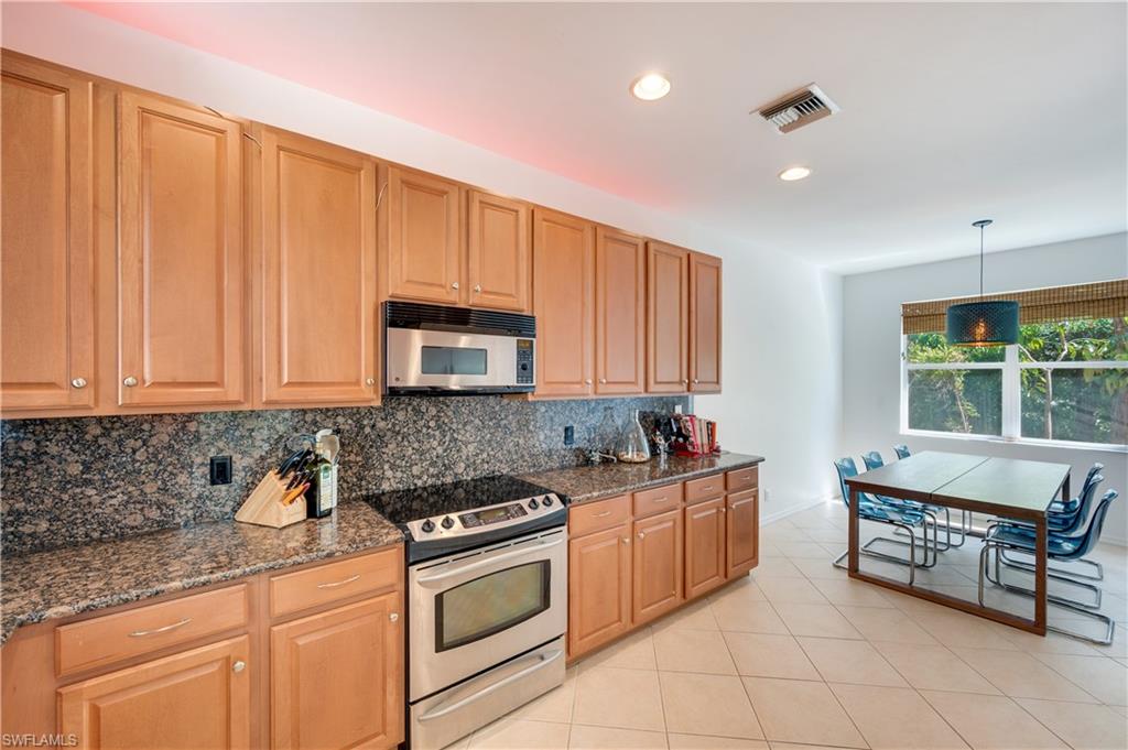 5738 Lago Villaggio Way Naples, FL 34104 - Photo 9 of 28 a kitchen with stainless steel appliances granite countertop a stove a sink and white cabinets