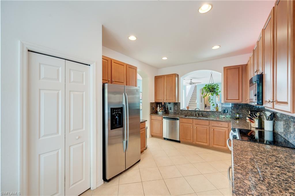 5738 Lago Villaggio Way Naples, FL 34104 - Photo 10 of 28 a kitchen with stainless steel appliances granite countertop a refrigerator and a stove top oven