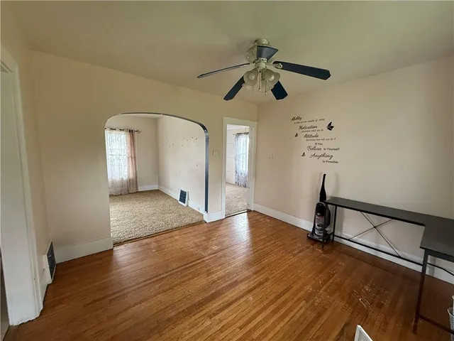 a view of empty room with wooden floor and fan