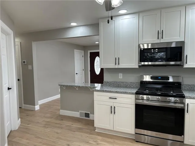 a kitchen with stainless steel appliances granite countertop a stove a sink and a microwave