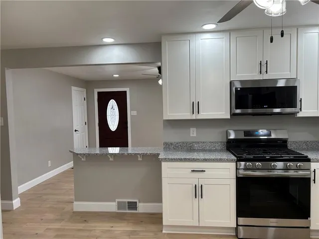a kitchen with stainless steel appliances granite countertop a stove a sink and a microwave