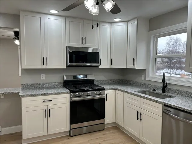 a kitchen with stainless steel appliances granite countertop white cabinets granite counter tops and a wooden floors