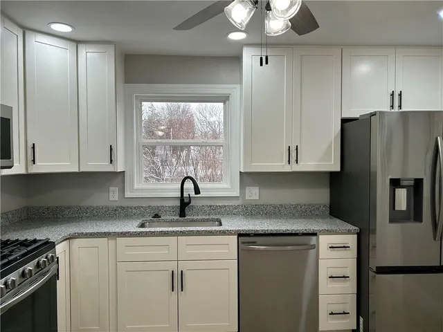 a kitchen with stainless steel appliances granite countertop a sink a stove and refrigerator