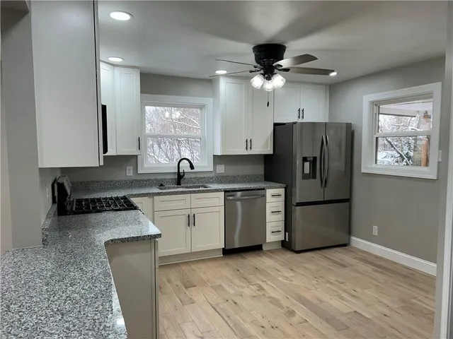 a kitchen with a refrigerator a sink cabinets and wooden floor