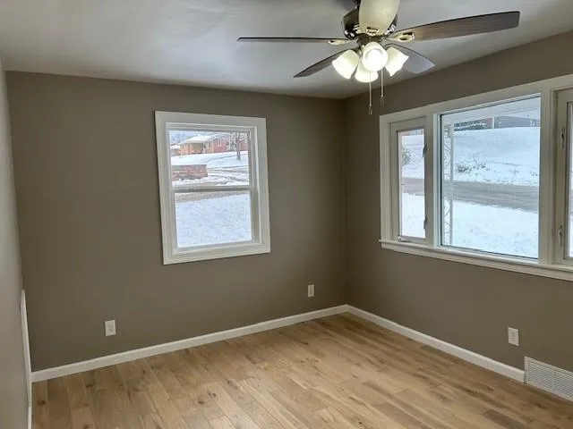 a view of an empty room with a window and wooden floor