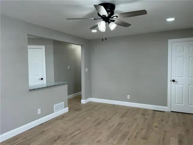 a view of an empty room with a window and wooden floor