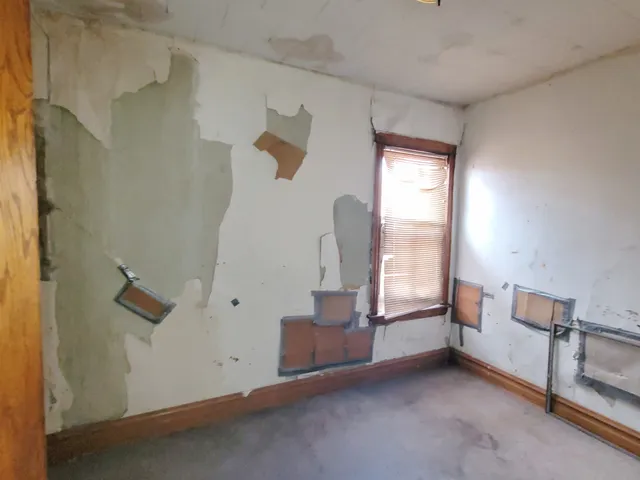 an empty room with a fireplace and windows