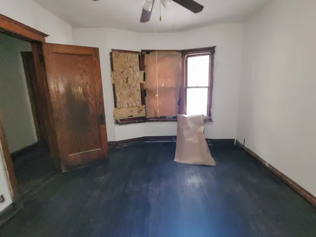 a view of empty room with wooden floor and fan