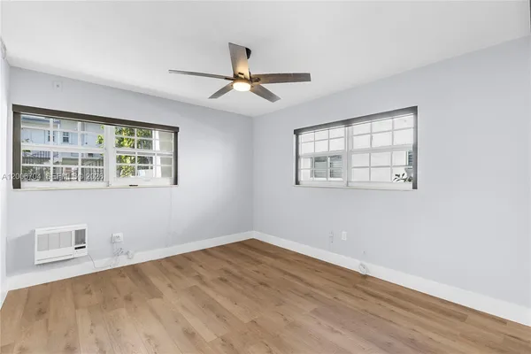 a view of empty room with wooden floor and fan