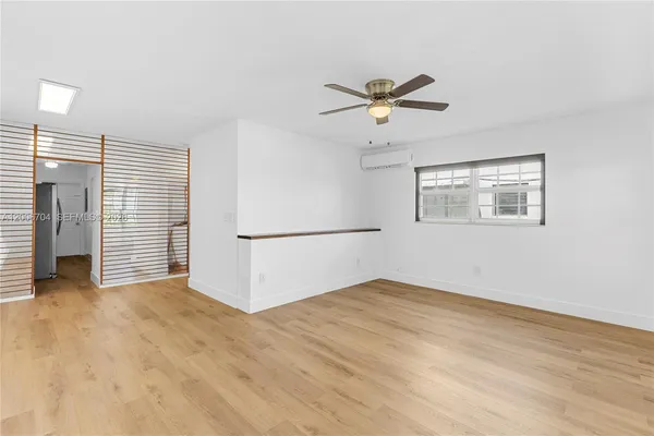 a view of empty room with wooden floor and ceiling fan