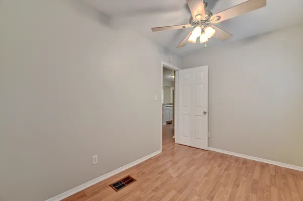 an empty room with a ceiling fan and wooden floor