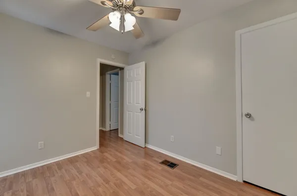 an empty room with wooden floor closet and windows