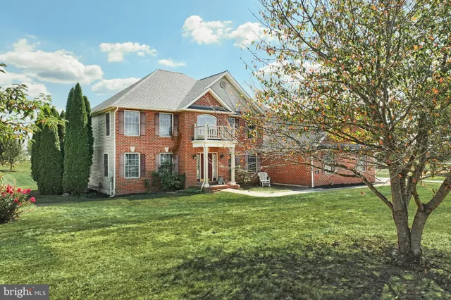 a view of a house next to a big yard and large trees