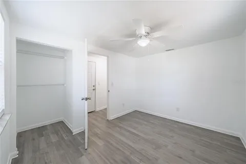 an empty room with wooden floor and ceiling fan