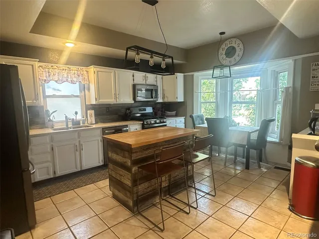 a kitchen view with stainless steel appliances kitchen island granite countertop a stove and a sink