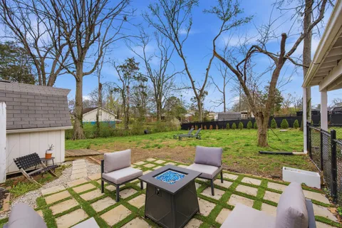 a view of a patio with couches table and chairs with a barbeque grill and a big yard and large trees