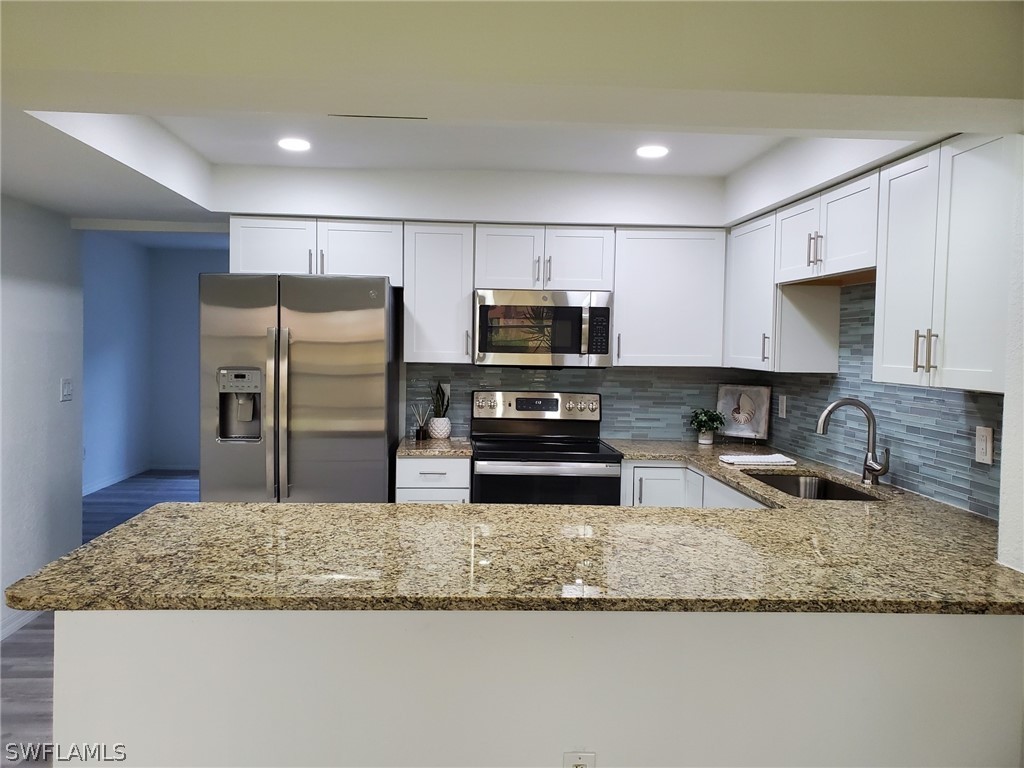 a kitchen with granite countertop a sink a center island stainless steel appliances and a counter space