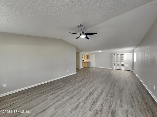 a view of empty room with wooden floor and ceiling fan