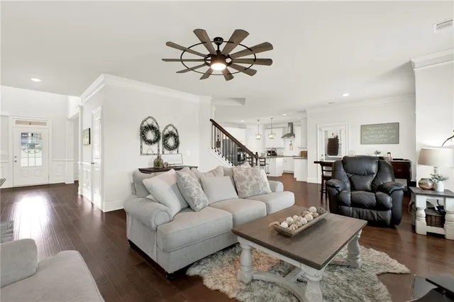 a kitchen with stainless steel appliances kitchen island granite countertop a refrigerator a stove a sink and white cabinets with wooden floor