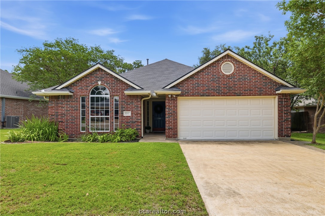 1707 Beaver Pond Court Bryan, TX 77807 - Photo 1 of 33 Brick facade residence featuring a front-facing attached garage, a mature lawn, and an arched window