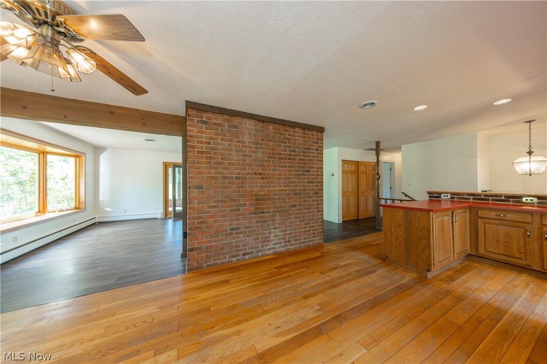 7969 Dines Road Novelty, OH 44072 - Photo 15 of 48 Open concept room featuring wood-finish flooring, a prominent brick accent wall, and a ceiling fan with integrated lighting