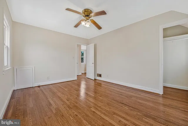 an empty room with wooden floor and ceiling fan