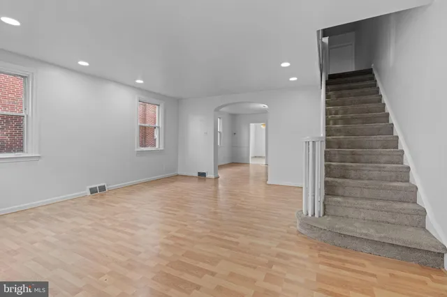 a view of an empty room with wooden floor and stairs