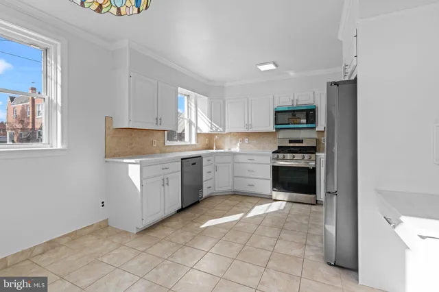 a kitchen with a sink a stove top oven and white cabinets