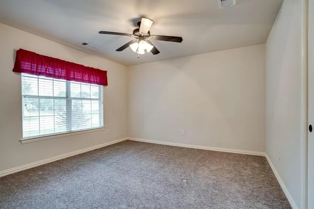 en empty room with windows and chandelier fan