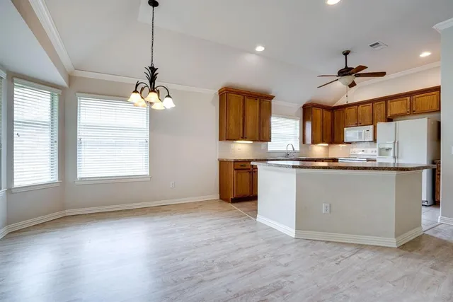 a kitchen with stainless steel appliances granite countertop a sink a oven a refrigerator and white cabinets with wooden floor