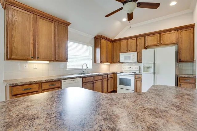 a kitchen with granite countertop a refrigerator and wooden cabinets