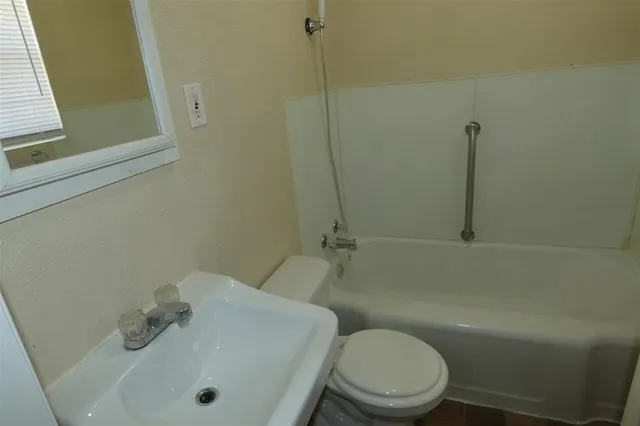 a white toilet sitting next to a bath tub