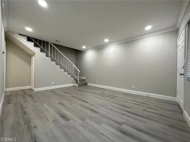an empty room with wooden floor and staircase