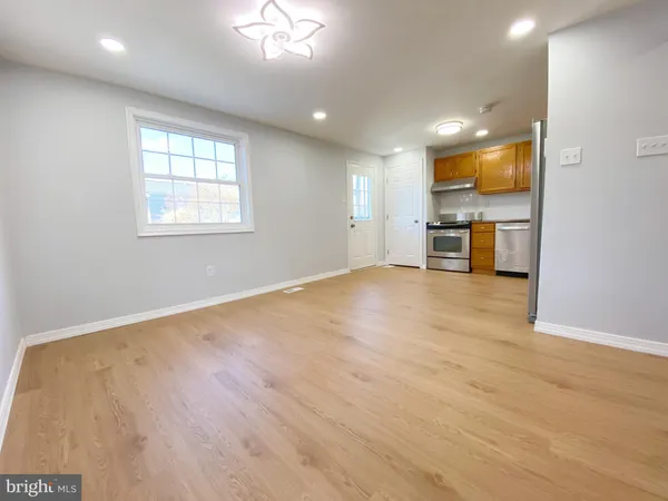 an empty room with wooden floor and a kitchen