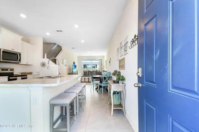 a dining hall with stainless steel appliances granite countertop a stove a sink a oven with a dining table and chairs