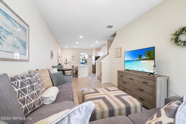 a living room with furniture kitchen view and a flat screen tv