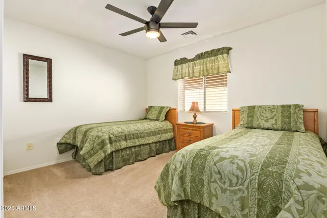 a bedroom with two beds and ceiling fan