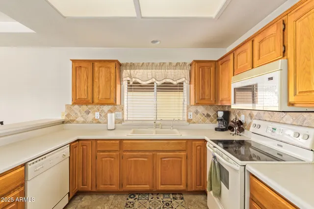 a kitchen with granite countertop a sink a stove cabinets and a window