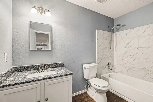 a bathroom with a granite countertop toilet sink and mirror