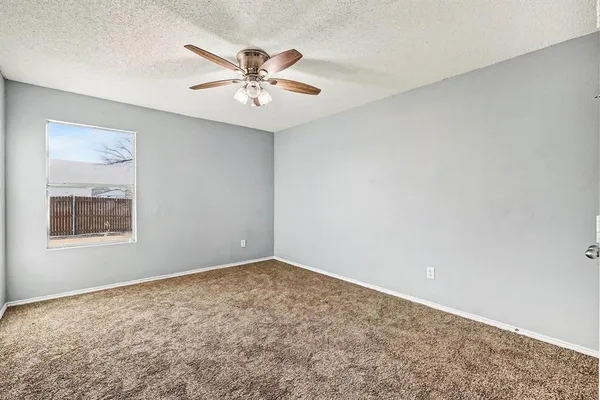 a view of an empty room with chandelier fan and a window