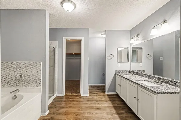 a bathroom with a granite countertop sink and a bathtub