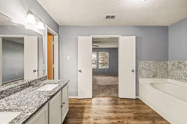 a bathroom with a granite countertop sink and a bathtub