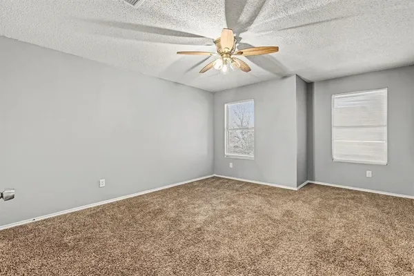 an empty room with windows and fan